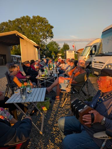 Teilnehmer sitzen an einer langen Tafel im Freien in der Abendsonne